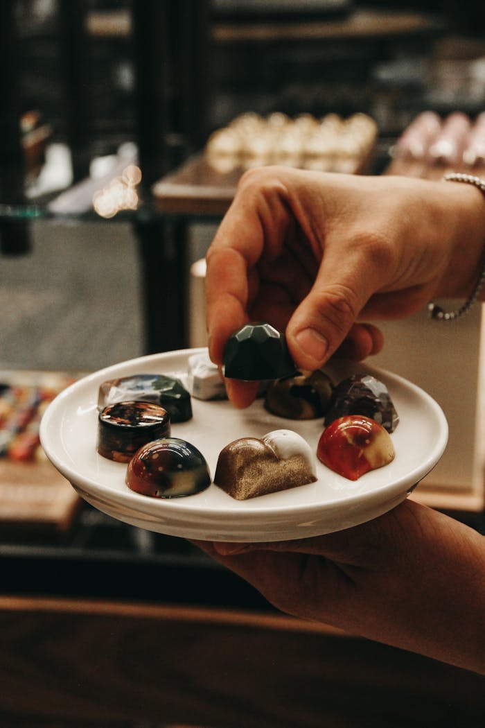 Assorted gourmet chocolates are elegantly presented with a hand showcasing their intricate designs.